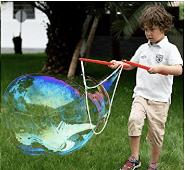 Un niño jugando con un kit de burbujas gigante afuera