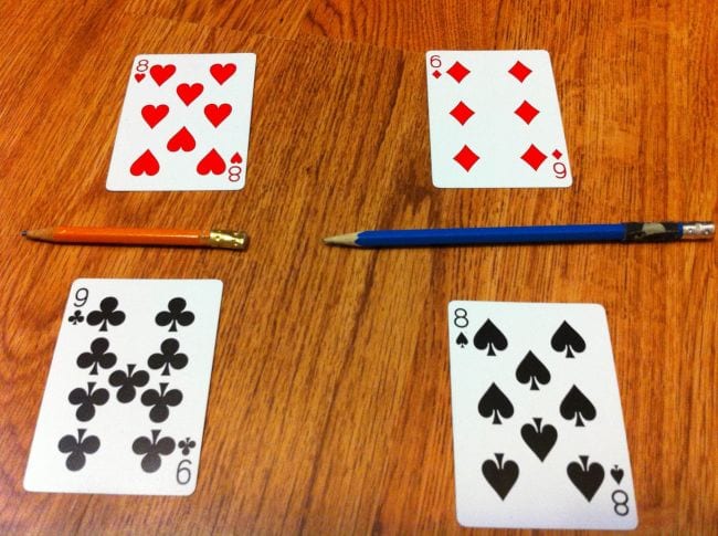 Se colocan cuatro cartas de juego sobre la mesa con un lápiz entre cada par que representa la puntuación (juego de puntuación)