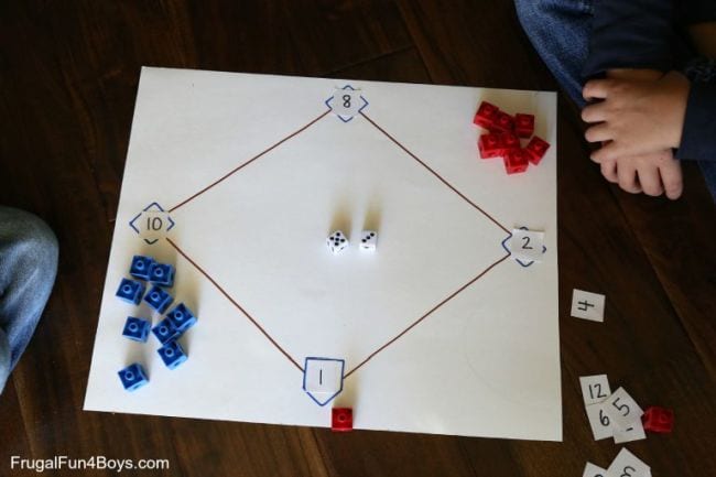Diamantes de béisbol dibujados en una hoja grande de papel con números y marcadores rojos y azules en cada base (juego de matemáticas de segundo grado)