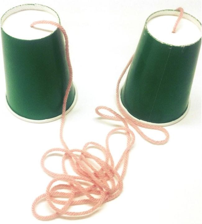 Dos vasos de papel verde conectados por una larga cuerda rosa en la parte inferior (experimento científico de primer grado)