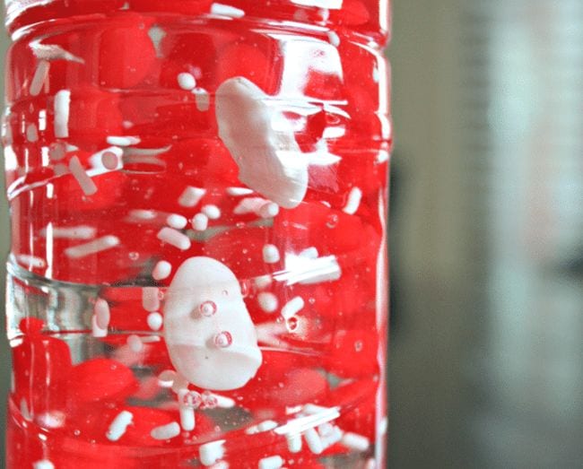 Botellas de plástico llenas de caramelo rojo y blanco y jarabe de maíz